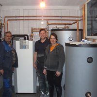 Zwei Männer und eine Frau stehen vor einem Boiler